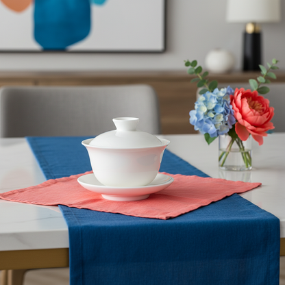 White covered serving bowl set on coral and blue table linens with flowers