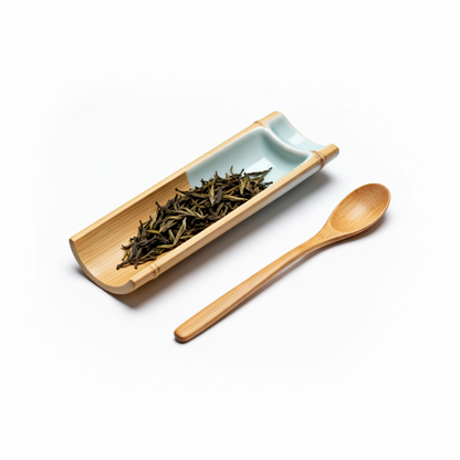 Light bamboo tea scoop beside a long bamboo tea-leaf tray with pale celadon insert on a white background