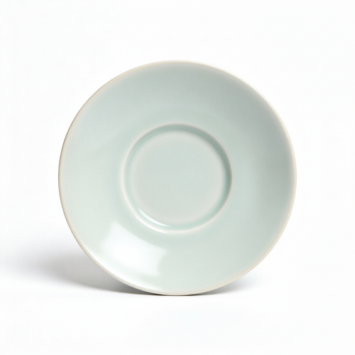 Pale celadon-white ceramic tea saucer with a central support ring on a white background